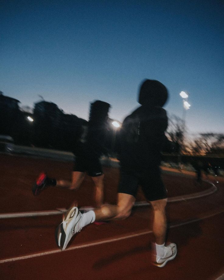 Runners on a track at dusk